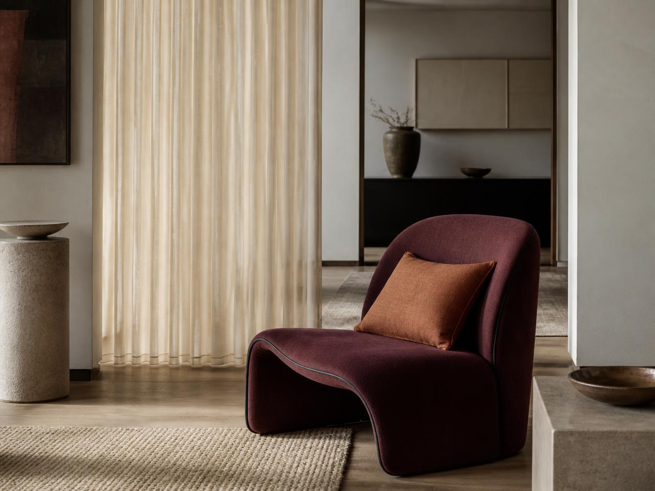 Burgundy upholstered lounge chair with ivory curtains and a copper cushion designed as a coordinated Kapaas furnishing concept